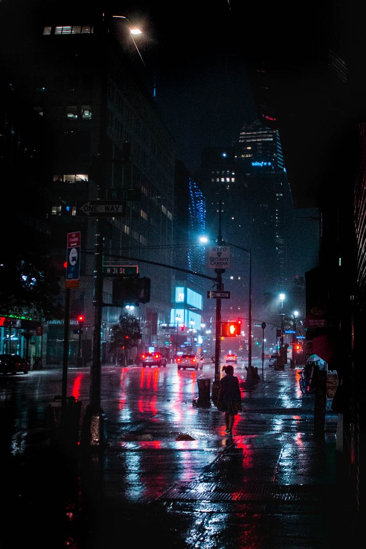 people walking down the street at night in the rain