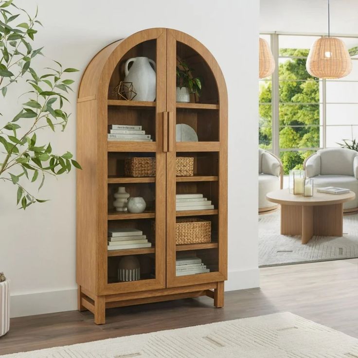 a wooden bookcase with baskets and books on it next to a plant in a living room