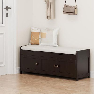 an entryway with a bench, coat rack and handbag hanging on the wall