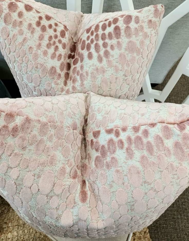 two pink pillows sitting on top of a white chair