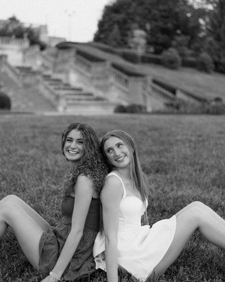 two women are sitting in the grass together