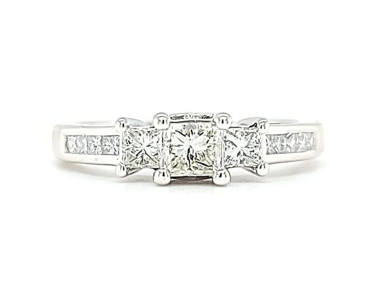 a three stone ring with princess cut diamonds on the sides and channeled shoulders, set in 18k white gold