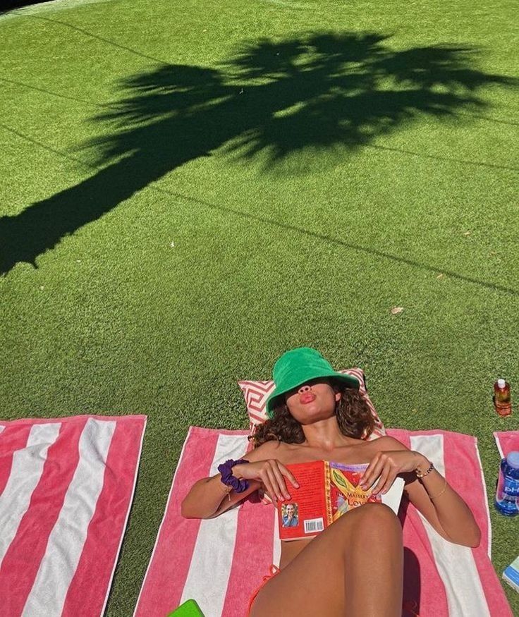 a woman laying on top of a red and white striped towel next to a tree