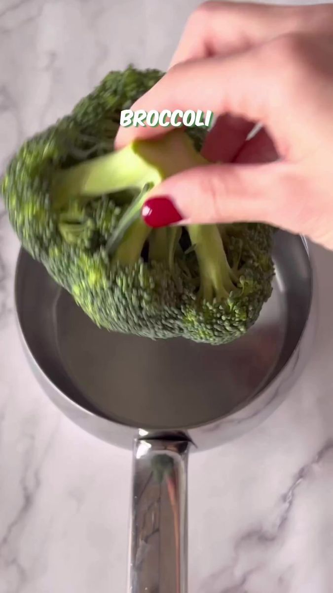 a person is touching broccoli on the side of a faucet holder