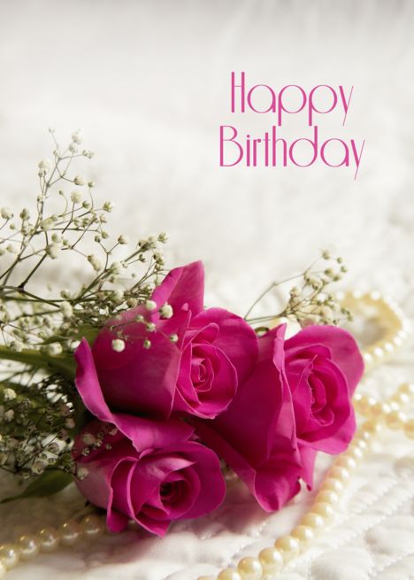 three pink roses and baby's breath on a white blanket with pearls around it