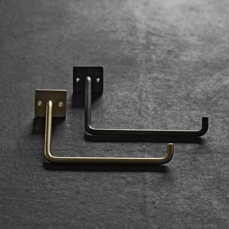 a pair of metal brackets on the floor with one holding an object in it's right hand