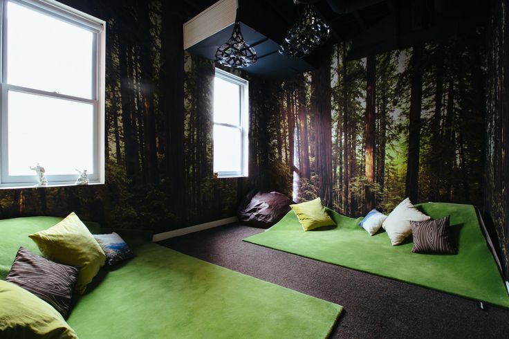 a room with green carpeted flooring and trees on the wall