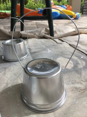 two metal pots sitting on top of a table next to an inflatable pool