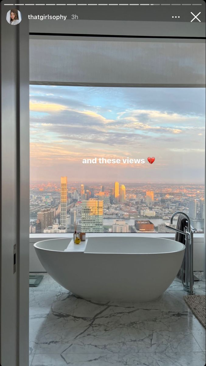 a large bathtub sitting in the middle of a bathroom next to a tall window