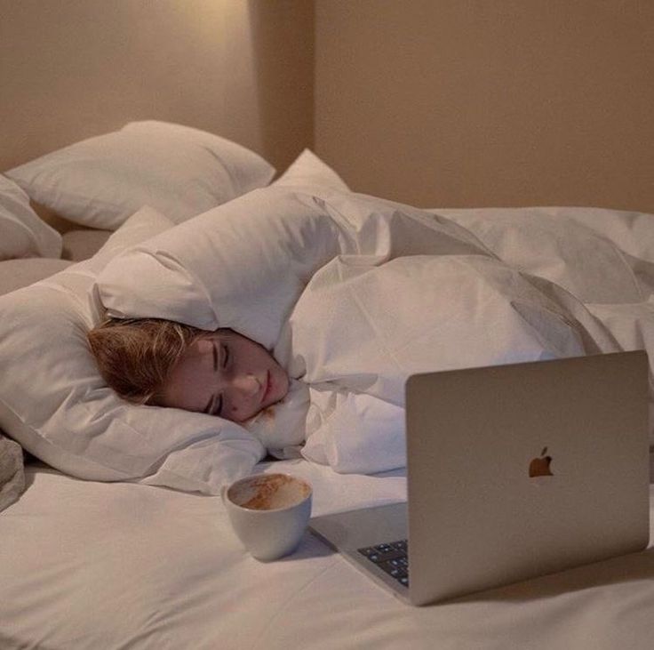 a young child laying in bed with an apple laptop computer on it's side