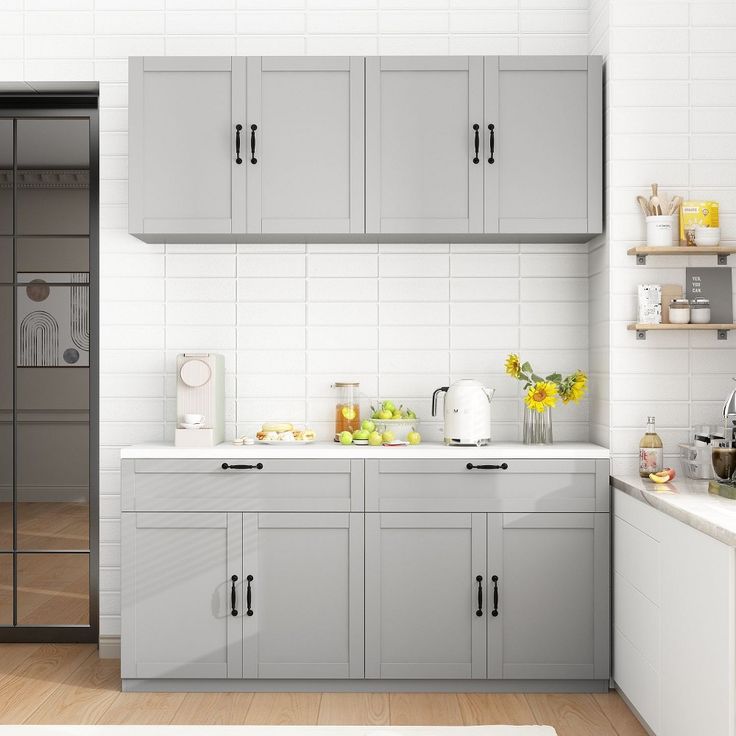 a kitchen with gray cabinets and white counter tops is shown in this image, there are yellow flowers on the counter