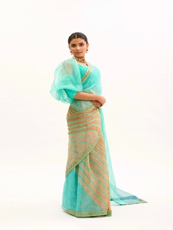 Featuring a Sea- Green Saree in Silk base with Handmade Lehariya and Gota Patti border. It is paired with matching Modal Satin Petticaot and Silk base Puff Sleeves Stitched Blouse. Fabric: Pure Silk Organza, Habutai Silk, Pure Modal Satin Lining Fabric - Cotton Color: Sea Green Embroidery & Embellishments: Gota Patti Blouse Neck: Sweetheart Fit: Fitted at bust and waist Note: The product will be delivered within 3-4 weeks of the order placed The color and size can be customized Wash Care - Dry c Reception Blouse Piece In Georgette With Zari Weaving, Georgette Blouse Piece With Zari Weaving For Reception, Eid Georgette Sets With Zari Weaving, Pista Green Saree With Dupatta For Reception, Semi-stitched Pista Green Saree For Reception, Pista Green Saree For Reception With Traditional Drape, Pre-draped Banarasi Silk Saree With Cutdana For Reception, Anarkali Organza Dupatta With Zari Weaving, Zari Weaving Dupatta For Reception