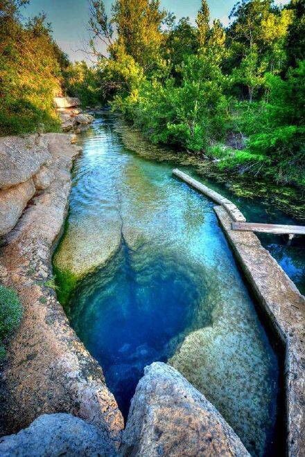 a river running through a forest filled with rocks and green trees on either side of it