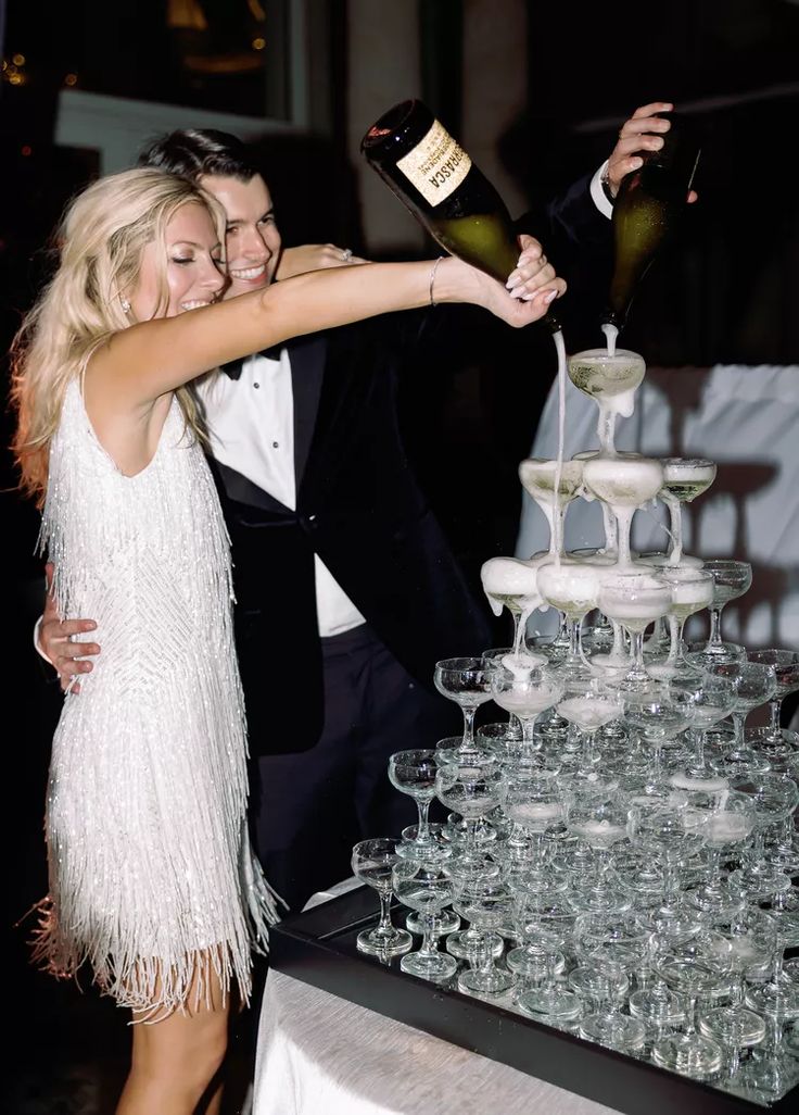 a man and woman standing next to each other in front of a table filled with wine glasses