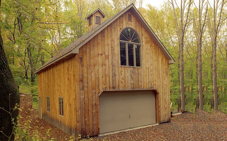 a wooden building with a garage in the middle of it surrounded by trees and leaves