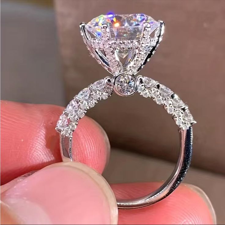 a close up of a person's hand holding a diamond ring