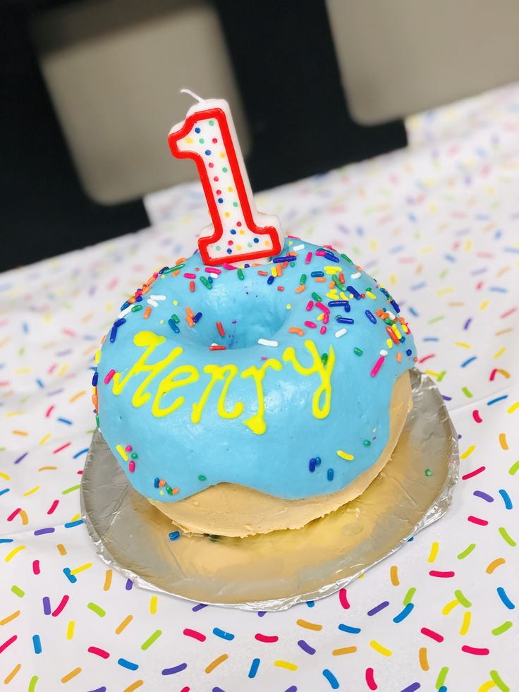 a blue frosted doughnut with a one candle on it sitting on top of a table