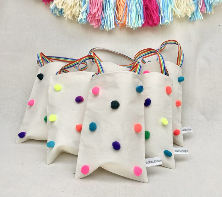 four bags with colorful pom - poms on them