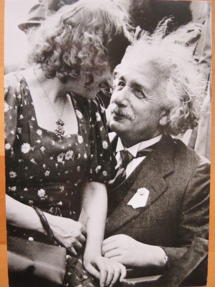 an old black and white photo of a man and woman looking at each other while sitting down