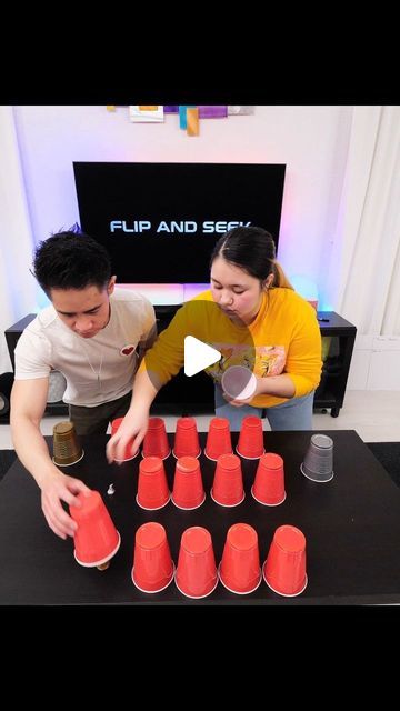 a man and woman standing next to each other at a table with cups on it