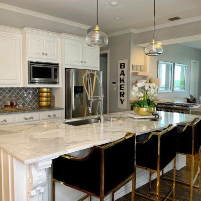 a kitchen with marble counter tops and gold accents on the island in front of the sink