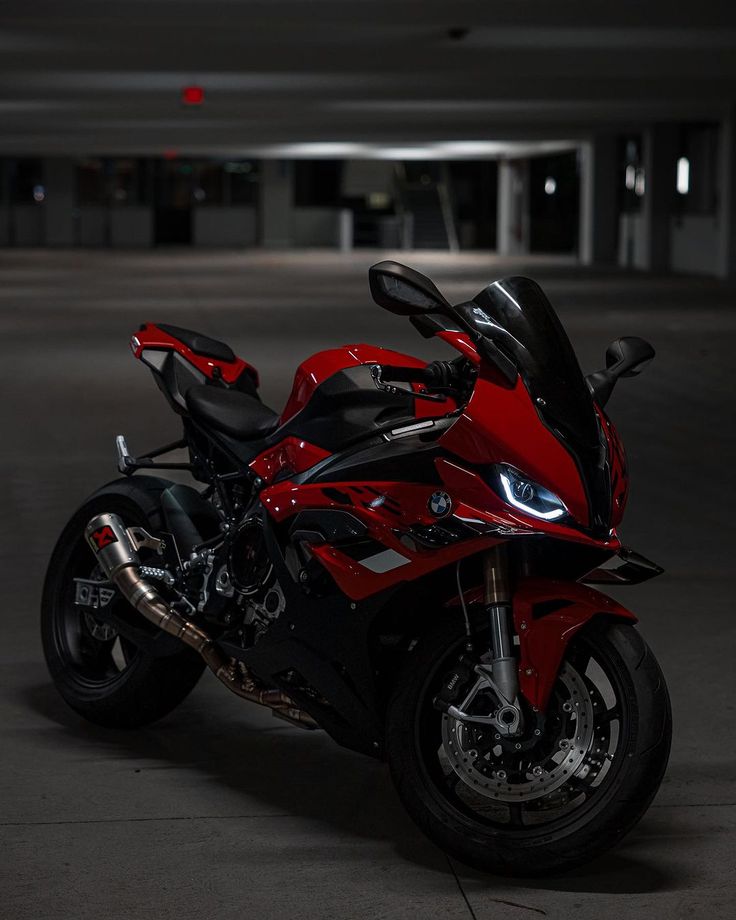 a red and black motorcycle parked in a parking garage with no one on the bike