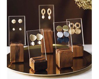 three wooden stand with earrings on them sitting on a table next to other jewelry items