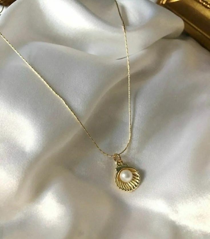 Embrace the elegance of the ocean with this Gold-Plated Pearl Shell Necklace. This elegant piece features a beautifully crafted shell necklace that houses a lustrous pearl. Perfect for beach lovers and those who appreciate the subtle beauty of the sea, this necklace is perfect for both everyday and special occasion wear. The gold-plated chain adds a touch of elegance, making it a timeless addition to your jewelry collection or a thoughtful gift for someone special. Details: * Color: Gold * Material: Gold-plated alloy, imitation pearl * Pendant Size: Approx. 1 cm x 1 cm (shell and pearl) * Chain Length: 45 cm (18 inches) with adjustable extension * Closure: Parrot clasp * Care Instructions: Avoid contact with water, perfume and other chemicals. Store in a dry place when necklace is not in u Elegant Cheap Shell Necklaces, Shell-shaped Pearl Pendant Jewelry, Shell-shaped Jewelry With Pearl Pendant, Ocean-inspired Shell-shaped Pearl Pendant Jewelry, Elegant Shell Pendant As A Gift, Elegant Shell Pendant As Gift, Elegant Shell Pendant For Gift, Elegant Pearl White Jewelry For Beach, Shell Necklace With Pearl Pendant