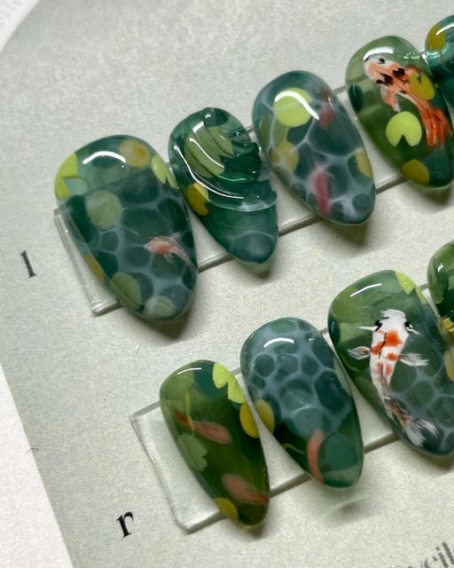 Veiled Nails on Instagram: "𝒌𝒐𝒊 🎏  Been wanting to do a koi fish set in a while! Complete with waterlilies 😌  ✦ 𝑺𝒊𝒛𝒆 𝒂𝒏𝒅 𝑺𝒉𝒂𝒑𝒆 - Medium Almond Natural @apresnailofficial ✦ 𝑭𝒍𝒂𝒔𝒉 𝑺𝒆𝒕  ✦ Using @sweetienailsupply Jin.B Crazy Top and @agehagel @trinagel_official  colours 。 。 。 。 。 。 #koinails #fishnails #koifishnails #koipond  #水墨画 #handpainted #3dnails #3dnailart #3dネイル #うるうるネイル #bluenails #nuancenails #pressons #veilednails #pressonnails #waternails #clearnails #greennails" Water Lily Nail Art, Nails With Fish, Koi Pond Nails, Goldfish Nails, Koi Fish Nail Art, Pond Nails, Koi Nails, Koi Fish Nails, Jellyfish Nails