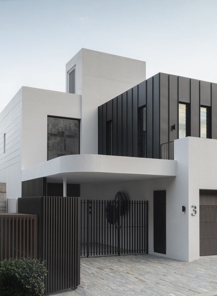 a modern house with black and white architecture on the outside, along with an iron gate