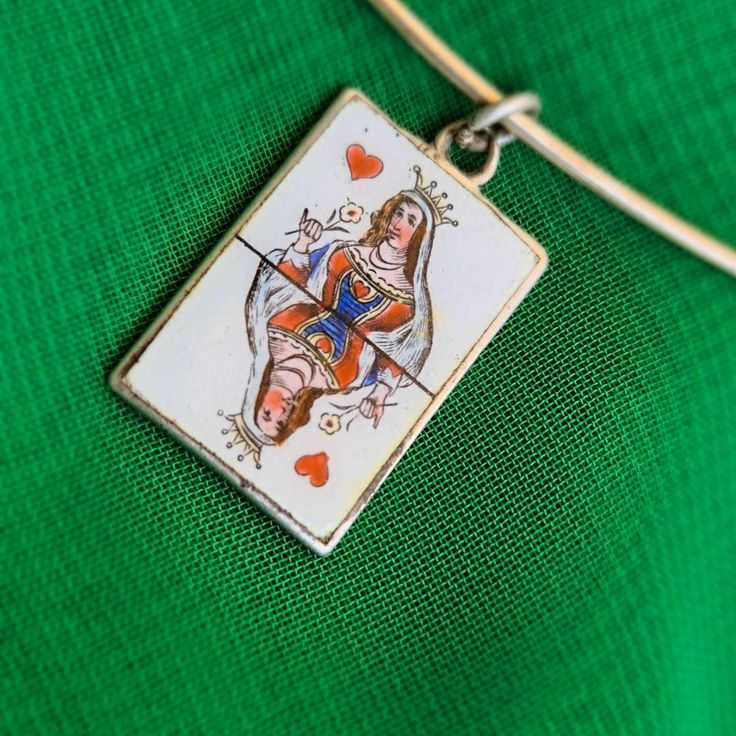 a close up of a key chain on a green cloth with a small square pendant