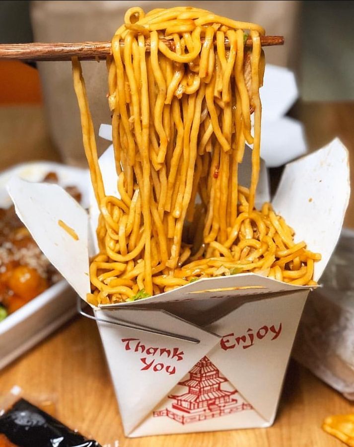 some noodles in a box with chopsticks sticking out of it