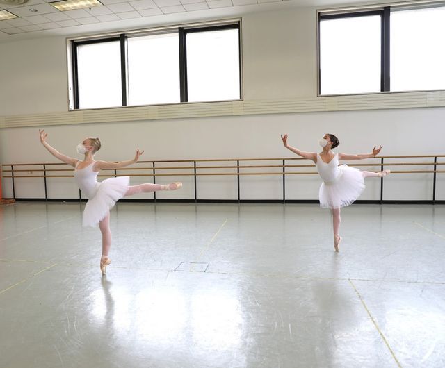 two ballerinas in white tutus are practicing ballet