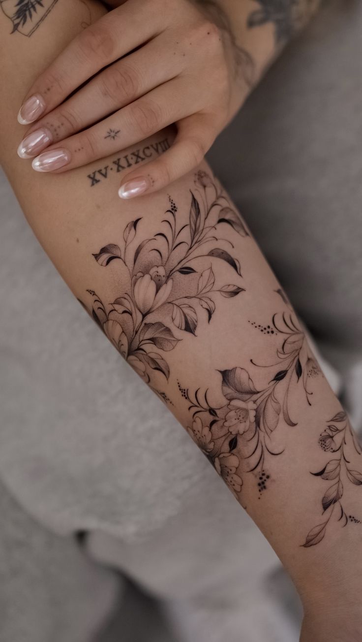 a woman's arm with tattoos on it and flowers in the middle of her arm