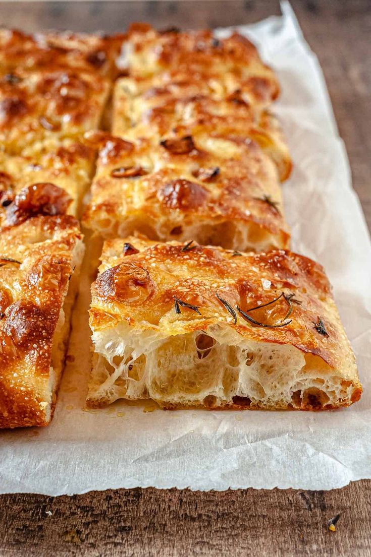 a close up of bread on a piece of parchment paper with text overlay that reads focaccia bread recipe with roasted garlic and rosemary