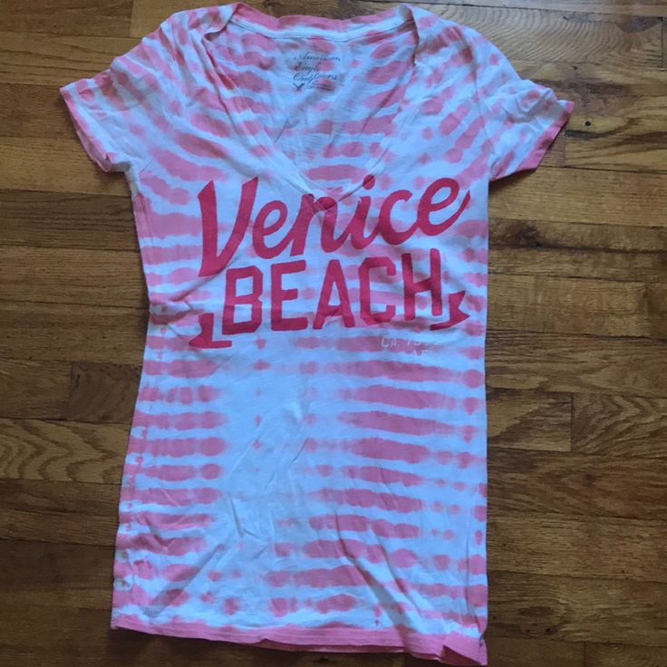 V-Neck Venice Beach American Eagle Shirt. Pink And White Design. Never Worn. V-neck T-shirt For Summer Vacation, Summer Vacation V-neck T-shirt, V-neck Cotton T-shirt For The Beach, Summer V-neck T-shirt For Vacation, Trendy V-neck T-shirt For Vacation, V-neck Graphic Print T-shirt For Vacation, Casual V-neck T-shirt For Vacation, Summer V-neck Graphic Print Top, White V-neck Summer T-shirt