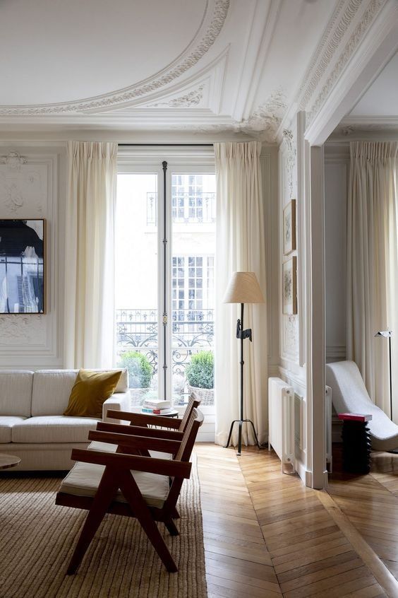 a living room filled with furniture and a large window covered in white draping