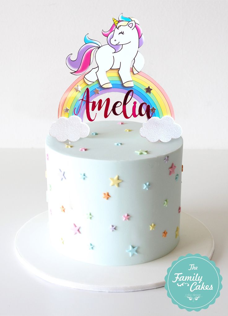 a white cake topped with a rainbow and an unicorn topper on top of it