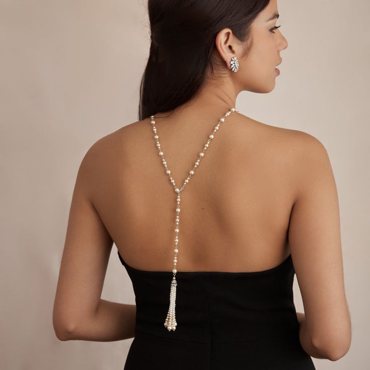 The Carina necklace is the perfect piece for adding glamour to the front and back of your bridal gown. Made to be versatile, this Czech glass pearl necklace can be worn with the crystal-encrusted tassel facing front or at the back, leaving an elegant strand of pearls around the front of the neck and accentuating any open-back gown. All jewelry is made to order in our New York City design studio. Please allow 7-14 business days for production from the order date. Measurements: 30.75" L Long Pearl Pendant Necklace For Parties, Elegant Pearl White Backdrop Necklace With Pearl Drop, Elegant Single Strand Beaded Necklaces For Formal, Elegant Pearl White Lariat Jewelry, Long Pearl Necklace With Pearl Charm For Party, Elegant Formal Beaded Necklace With Pearl Chain, Elegant Drop Necklace With Pearl Chain, Elegant Pearl Backdrop Necklace With Pearl Drop, Elegant Formal Pearl Chain Beaded Necklace