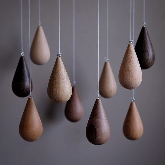 several wooden drops hanging from strings on a wall