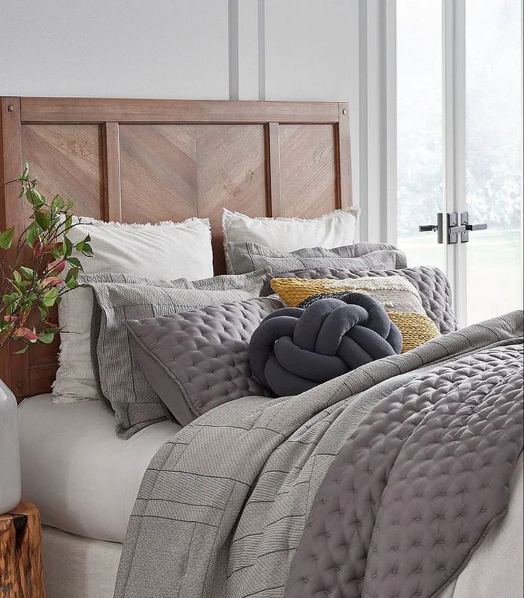 a bed with grey comforter and pillows on it