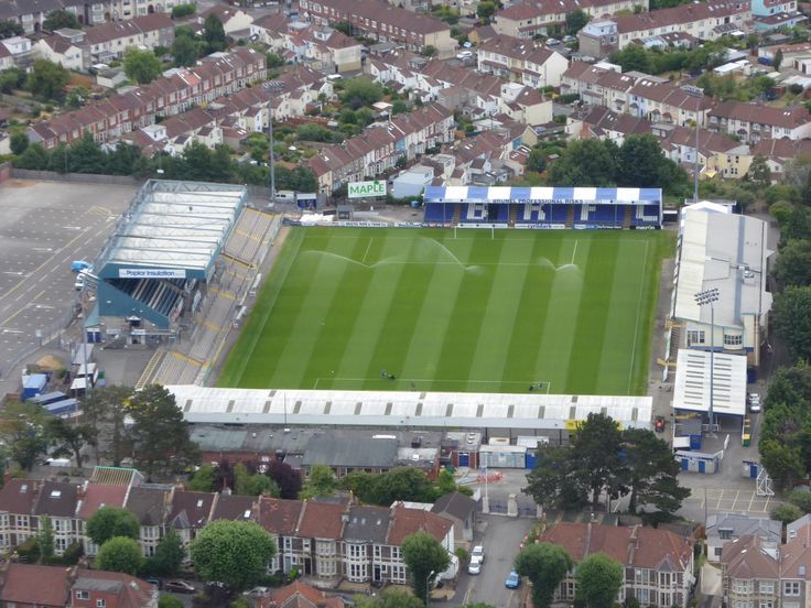 an aerial view of a soccer field with houses in the background and buildings around it