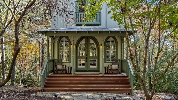 a gazebo in the woods with steps leading up to it and two chairs on the porch