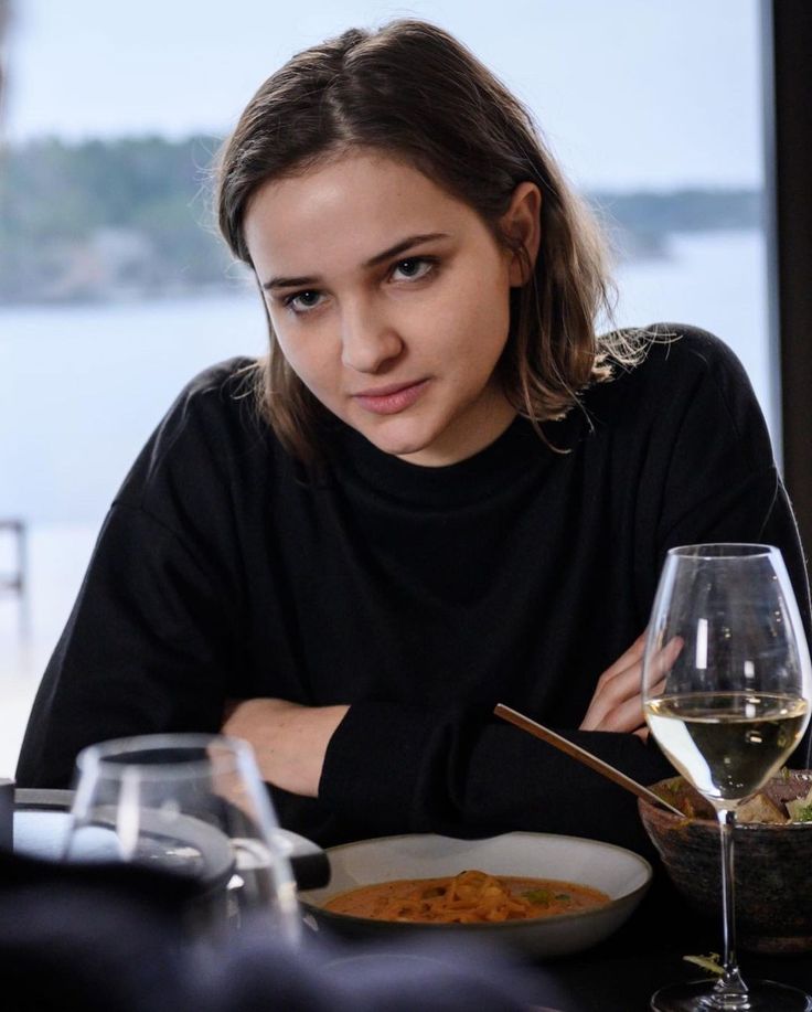 a woman sitting at a table with a bowl of food in front of her