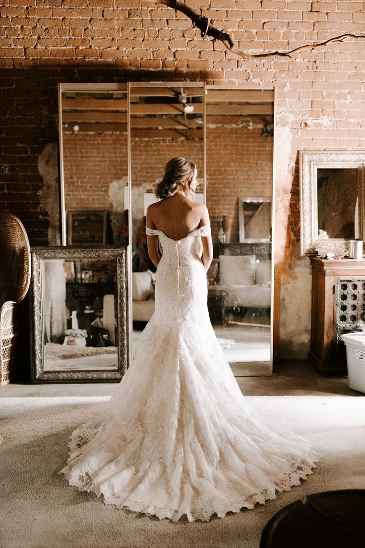 a woman in a wedding dress is looking at the back of her dress, and she has