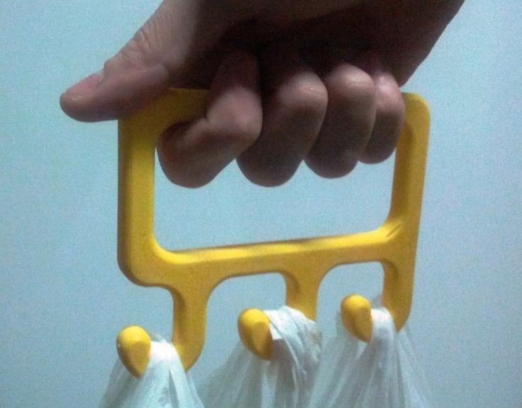 a hand holding a yellow plastic bag holder