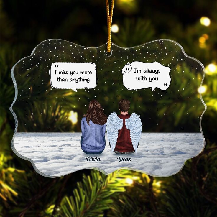 an ornament hanging from a christmas tree with two people sitting on the ground