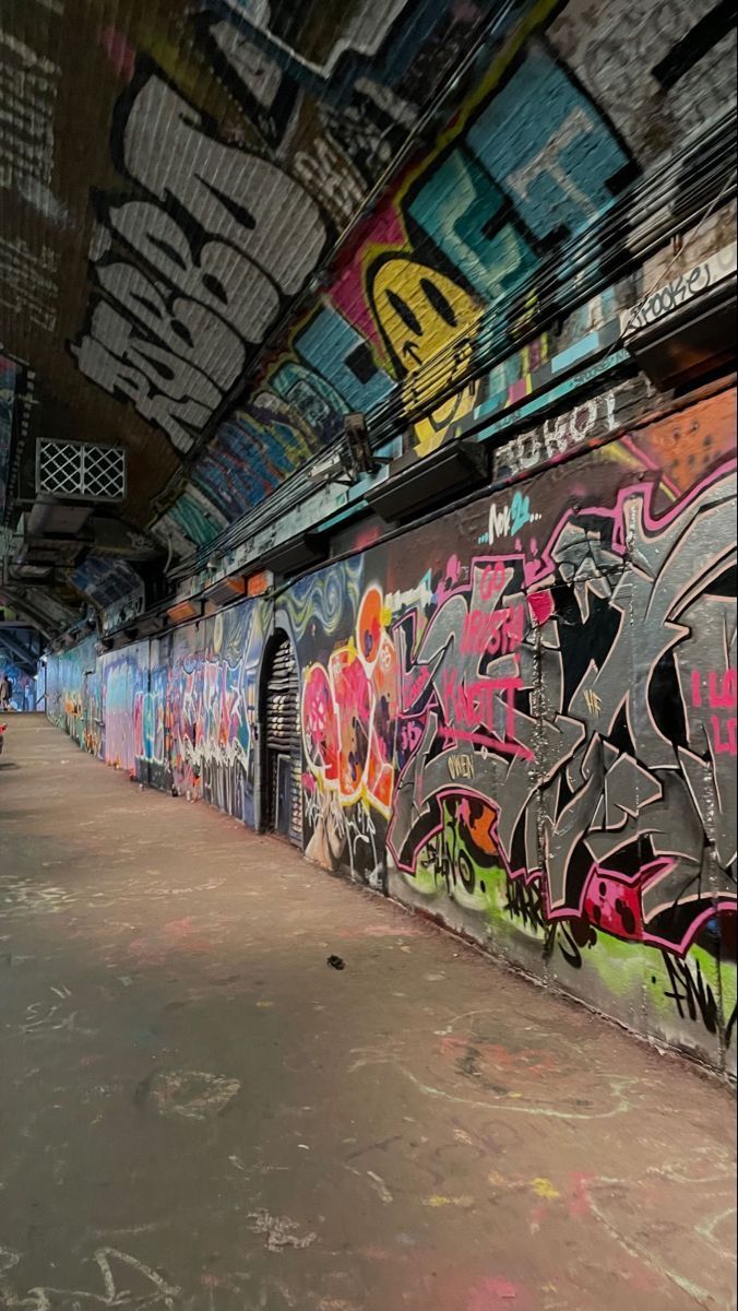 graffiti is painted on the side of a wall in an empty subway car station with people walking by