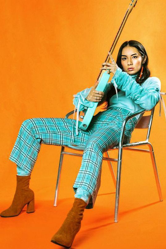 a woman is sitting in a chair with a guitar on her lap and holding an umbrella