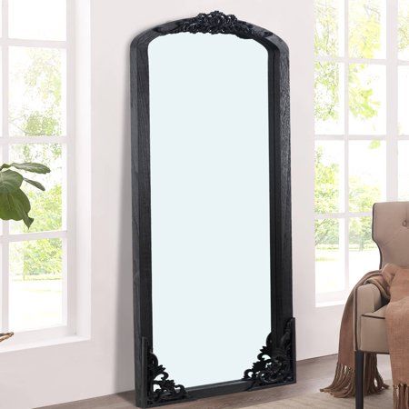 a large mirror sitting on top of a wooden floor next to a chair and window